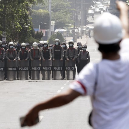 A demonstrator reacts on Friday as police officers block a road during a protest in Yangon against Myanmar’s military coup. Photo: EPA
