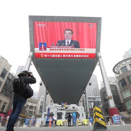 Chinese Premier Li Keqiang makes government report at the opening of NPC displayed in a big TV screen at a shopping area in Beijing on Friday morning, March 5, 2021. Photo: Simon Song