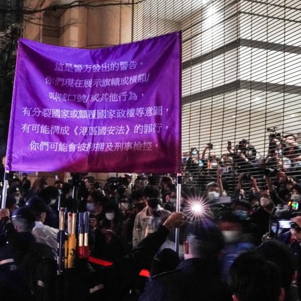 Police officers raise a flag warning supporters of the 47 pro-democracy activists charged with subversion outside West Kowloon Magistrates’ Courts in Hong Kong on Thursday, March 4. Photo: Felix Wong
