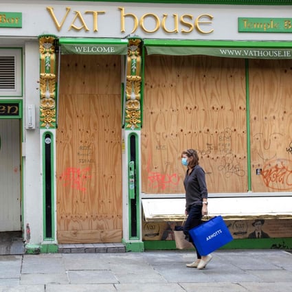 A woman walks past a boarded up bar in Dublin in October last year. Photo: AFP