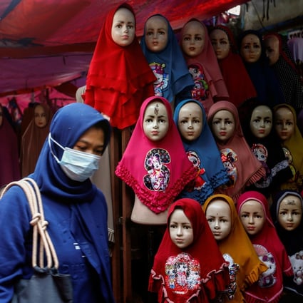 Women walk past hijabs for sale at the Tanah Abang textile market in Jakarta, Indonesia, on Tuesday. Photo: Reuters