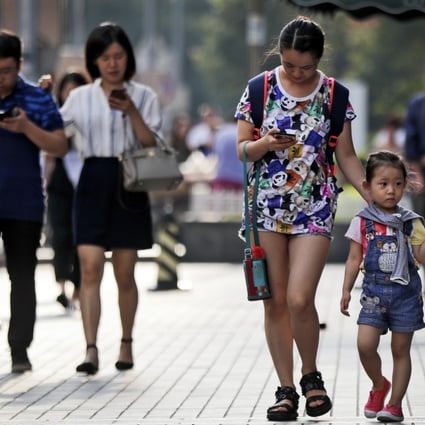 Pedestrians view their smartphones as they walk along a street in Beijing. Photo: AP