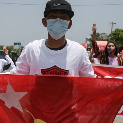 A demonstrator carries a National League for Democracy flag during a rally in Mandalay. Photo: EPA