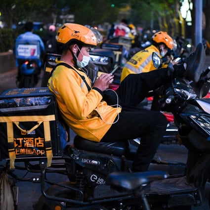 Meituan delivery riders rest on their electric scooters while waiting for orders outside a restaurant in Beijing on April 26, 2021. Photo: AFP