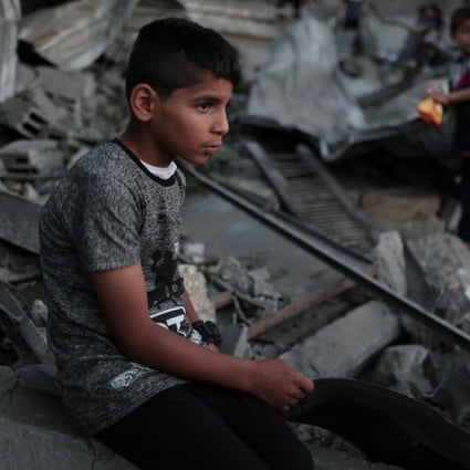 A Palestinian boy sits on the rubble of a house destroyed by Israeli air strikes in the southern Gaza Strip city of Khan Younis on Friday. Phtoto: Xinhua