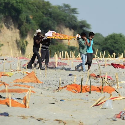 People carry a body past shallow graves on the banks of the Ganges River. Photo: AFP