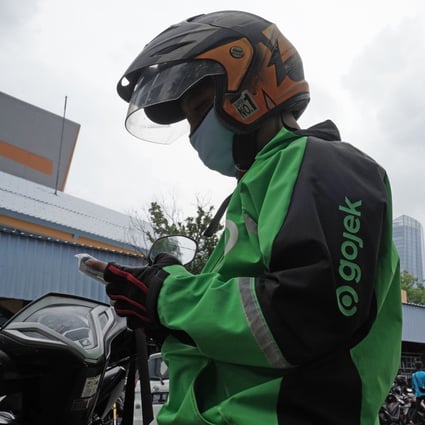 A Gojek driver checks his mobile phone in Jakarta in January. Southeast Asia technology companies Gojek and Tokopedia plan to combine in the biggest merger ever in Indonesia. Photo: Bloomberg