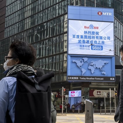 Pedestrians stand in front of a screen showing a message marking the listing of Baidu Inc. on the Hong Kong Stocks Exchange in Hong Kong on March 23, 2021. Photo: Bloomberg