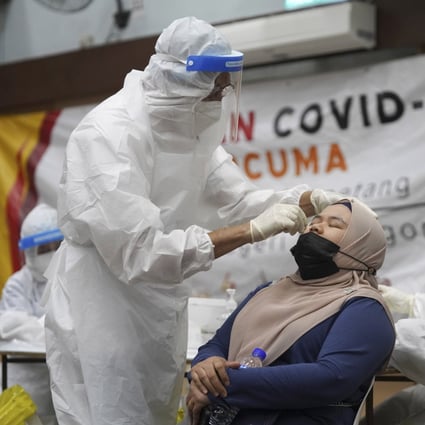 A medical worker collects a swab sample from a woman at a Covid-19 testing centre in Ulu Klang, Kuala Lumpur. Photo: AP