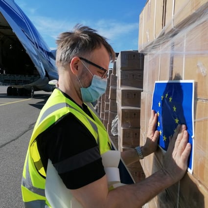 A Red Cross worker sticks an EU flag sticker on a shipment of ventilators from Germany before it is loaded onto a cargo plane bound for New Delhi, India, at Helsinki airport in Finland on May 11. A total of 18 EU member states have pledged medical aid to India. Photo: AFP