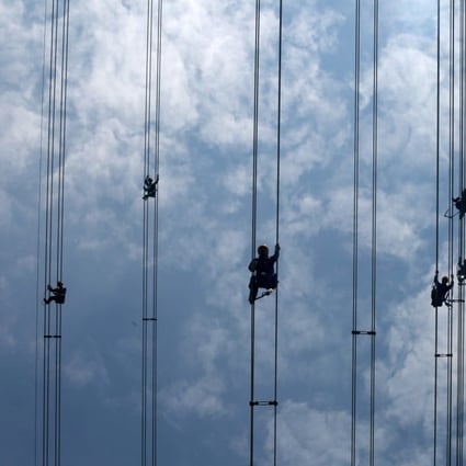 Workers of grid operator China Southern Power Grid inspect power cables connecting transmission towers in Dongguan, Guangdong province in May 2018. Photo: Reuters
