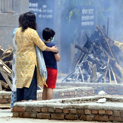 A family looks at the funeral pyres for a Covid-19 victim in New Delhi. Photo: Xinhua