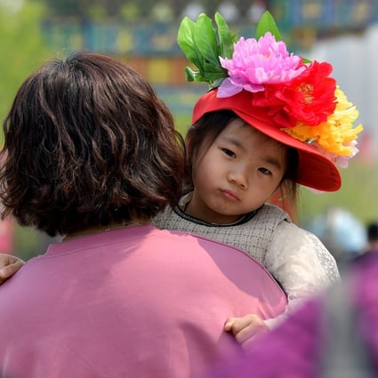 A woman carries a girl as they visit a peony garden in Heze, in east China’s Shandong province, on April 8. In 2020, the country saw only 12 million births, the lowest number in at least six decades. Photo: Xinhua