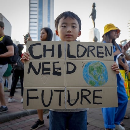 A boy holds a sign during a climate change strike in Bangkok, Thailand, on November 29, 2019. The global race for net zero is like a 2050 Olympics where every city and country shows it can win, not just for its community but for the whole world. Photo: EPA-EFE
