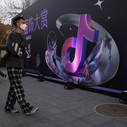 A woman speaks on her phone near the logo for Douyin, the Chinese version of TikTok, in Beijing on March 31. After Tencent’s vice-president compared personalised short videos to pig feed, ByteDance fired back on Friday, calling the comments stigmatising. Photo: AP