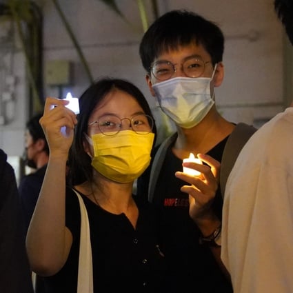 People holding candles stand on the street in Causeway Bay. Photo: Sam Tsang