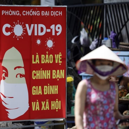 A woman walks past a sign bearing Covid-19 prevention advice in Hanoi. Photo: EPA-EFE