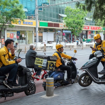 Meituan food delivery riders gather around their motorcycles in Beijing on April 21, 2021. Photo: Bloomberg
