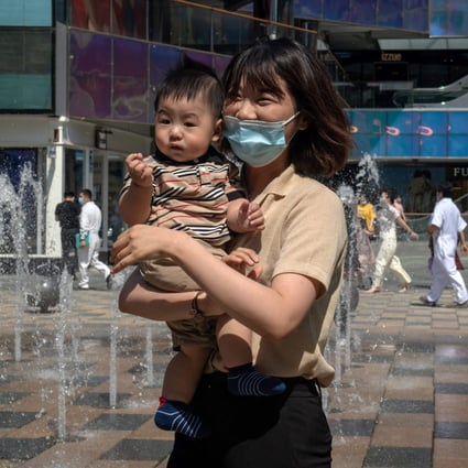 A woman holds her child outside a shopping centre in Beijing on June 1, a day after China announced it would allow couples to have three children. Photo: AFP