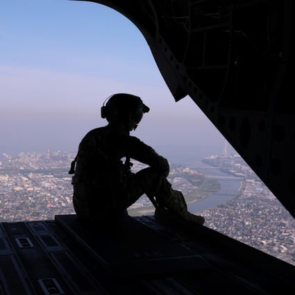 A US soldier looks out over Tokyo from the back of a military transport helicopter in 2019. Photo: Reuters