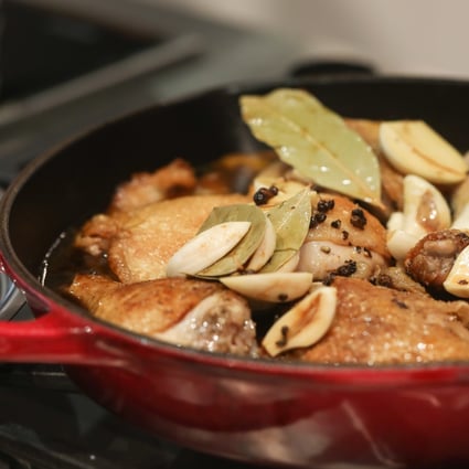 Chicken adobo simmers in a pan. Photo: Jonathan Wong