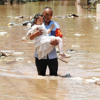 A village official evacuates a child from a flooded area on Monday following heavy rains in Dazhou, Sichuan province. Photo: AFP