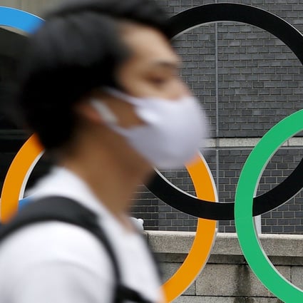 A pedestrian walks past the Olympic rings in Tokyo as the city counts down the final days to the Games. Photo: Kyodo