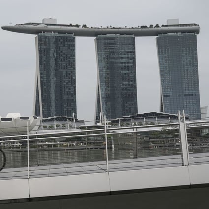 A man cycles along the Jubilee Bridge in front of the Marina Bay Sands in Singapore, which is experiencing a surge in coronavirus infections. Photo: EPA-EFE