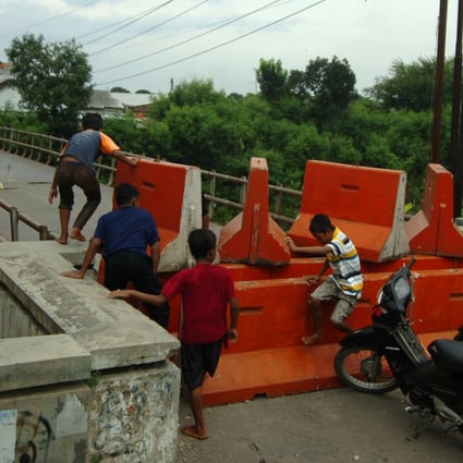 Children in Central Java Province play on barriers placed as part of movement restrictions amid surging Covid-19 cases in Indonesia. Photo: Reuters