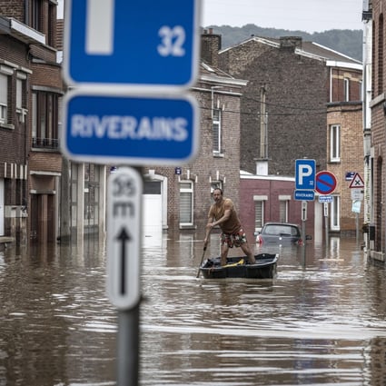 A man rows a boat down a residential street after flooding in Angleur, Belgium. There are many factors for flooding, but a warming atmosphere makes extreme weather more likely and frequent the world over. Photo: AP