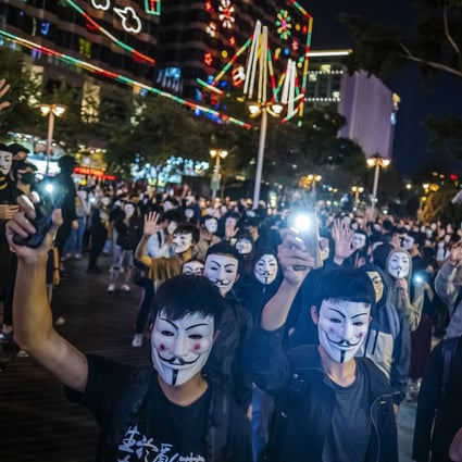 Mask-wearing protesters hold their smartphones aloft during a rally in the Tsim Sha Tsui district of Hong Kong in November 2019. Photo: Bloomberg