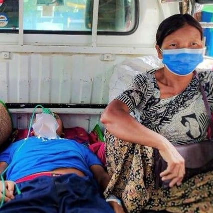 A relative sits with a coronavirus patient who is being taken to a hospital in the town of Kale, as Myanmar battles a deadly uptick in cases. Photo: Reuters