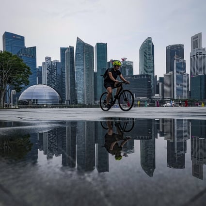 A cyclist reflected in a puddle rides past the skyline of Singapore’s financial district. A special purpose acquisition vehicle backed by Hong Kong billionaire Richard Li Tzar-kai is buying Singapore’s PropertyGuru, Southeast Asia’s biggest property technology company. Photo: EPA-EFE