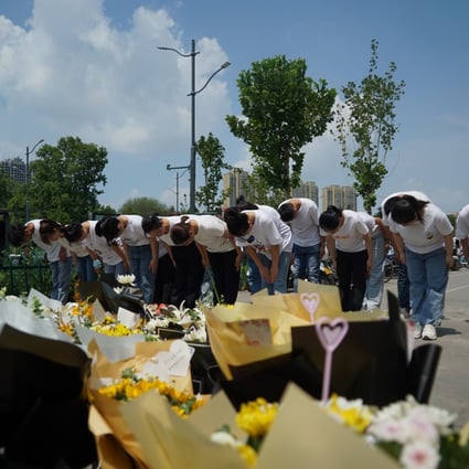 People bow to pay their respects outside the entrance to a subway station in Zhengzhou in central China's Henan Province, Tuesday, July 27, 2021. Photo: AP