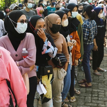 People wearing face masks queue to receive a dose of China's Sinovac vaccine during a mass vaccination programme at a school building in Jakarta on Monday. Photo: Reuters