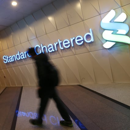 A man walks past a logo for Standard Chartered in Central. Photo: David Wong