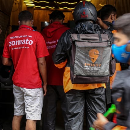 Delivery riders for Zomato and Swiggy, two Indian start-ups, wait to collect orders outside a restaurant in Mumbai. Photo: Bloomberg