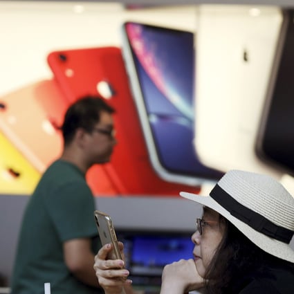 In this May 10, 2019, file photo, a customer looks at her iPhone at an Apple store in Beijing. Apple suppliers in China are currently scrambling to hire new workers for the ramp-up of the iPhone 13. Photo: AP