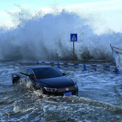 A car sitting in flood waters as waves caused by Typhoon In-Fa surge over a barrier along the coast in the Shandong provincial city of Qingdao in eastern China on July 25, 2021. Photo: AFP