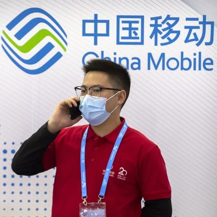 People wearing face masks talk on their cellphones near a booth for telecommunications firm China Mobile at the PT Expo in Beijing in October 2020. Photo: AP