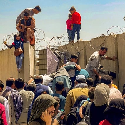 Crowds fleeing the Taliban advance brave barbed wire as they try to get inside Kabul’s international airport on Monday. Photo: Reuters