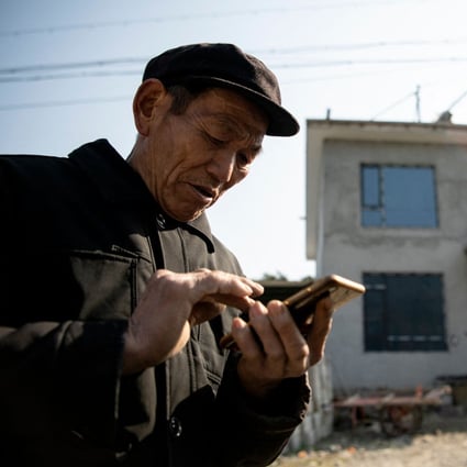A farmer uses his mobile phone in front of his new residence in Baojing county, in central China's Hunan province, in January. Photo: AFP