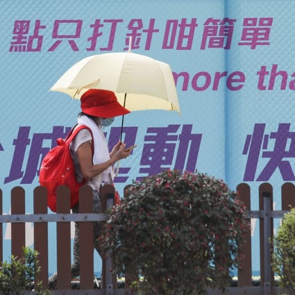 A woman walks past a sign urging Hong Kong residents to get vaccinated. Photo: Xiaomei Chen
