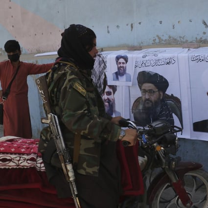 A Taliban fighter looks at Taliban flags and posters of leaders in Kabul, Afghanistan, on Wednesday. Photo: AP