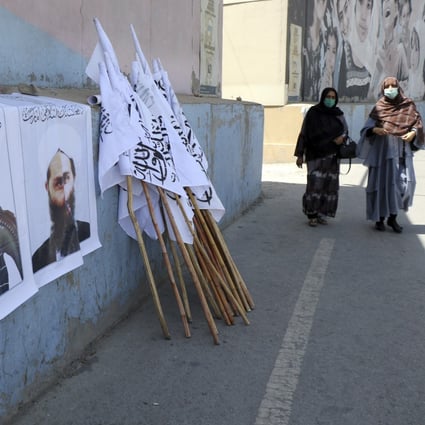 Afghan women walk by posters of Taliban leaders and flags in Kabul, Afghanistan, on August 25. Photo: AP