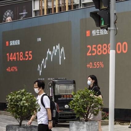Pedestrians walk past a public screen displaying the Shenzhen Stock Exchange and the Hang Seng Index figures in Shanghai. Photo: Bloomberg