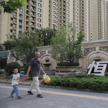 Residents walk near the Evergrande corporate name outside a residential complex in Beijing in September 2021 as the developer’s liquidity crisis infects market sentiment. Photo: EPA-EFE