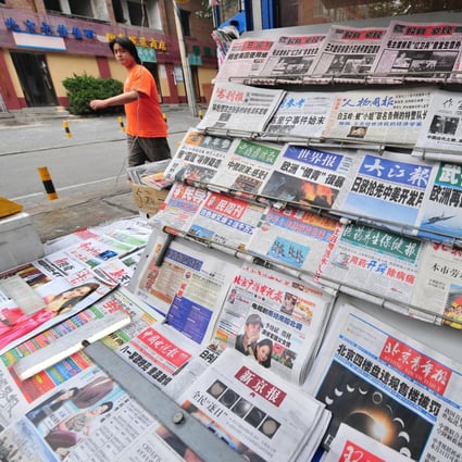 A man walks past a display of newspapers at a news-stand in Beijing on July 23, 2009. In a new draft document reiterates rules in place since 2005 banning private capital in news media, which the government has previously selectively enforced. Photo: AFP
