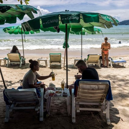 People under the shade of a beach umbrella in Phuket, Thailand. Photo: AFP
