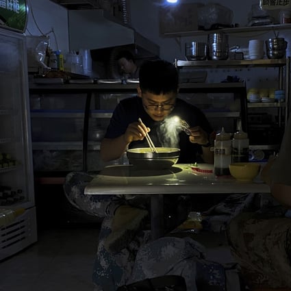 A man eats noodles by the light of his cellphone during a recent blackout in Shenyang, Liaoning province. Photo: AP